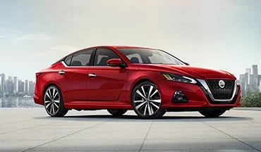2023 Nissan Altima in red with city in background illustrating last year's 2022 model in Valley Hi Nissan in Victorville CA